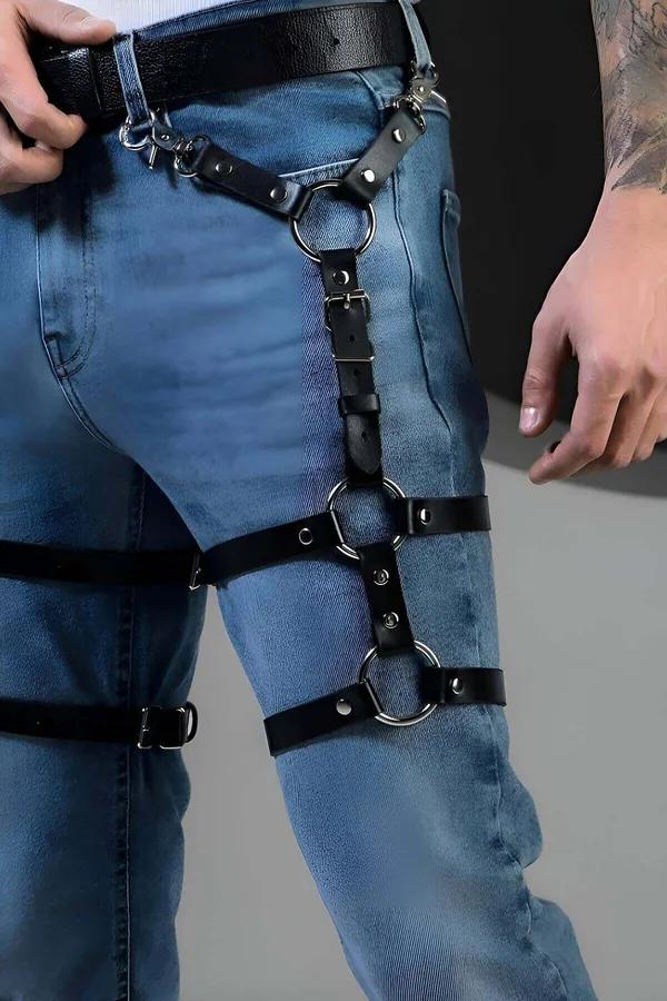 black faux leather leg harness with three silver O-rings worn over blue jeans, adjustable buckle straps from hip to knee