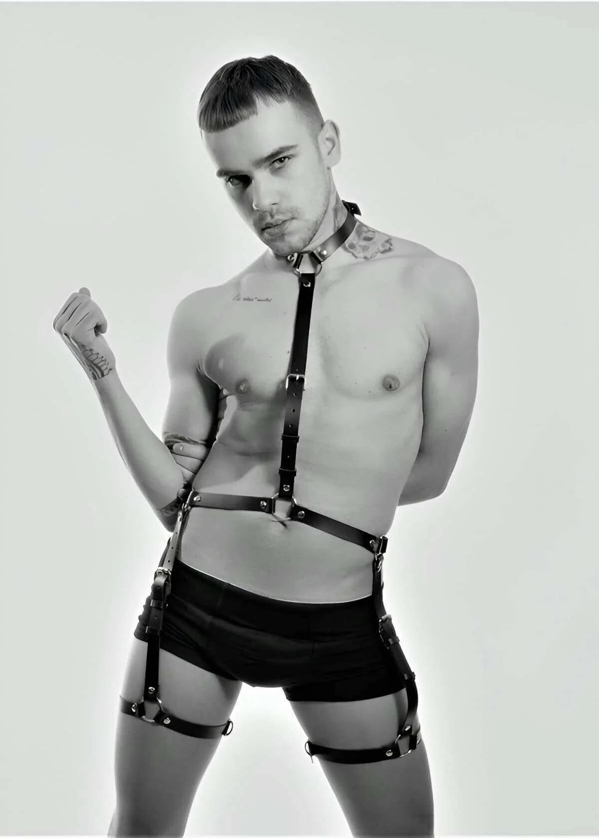 Black faux leather full body harness with collar, chest strap, waist band, and thigh garter loops on male model